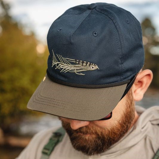 Man with beard wearing a navy hat with a streamer fly on the front
