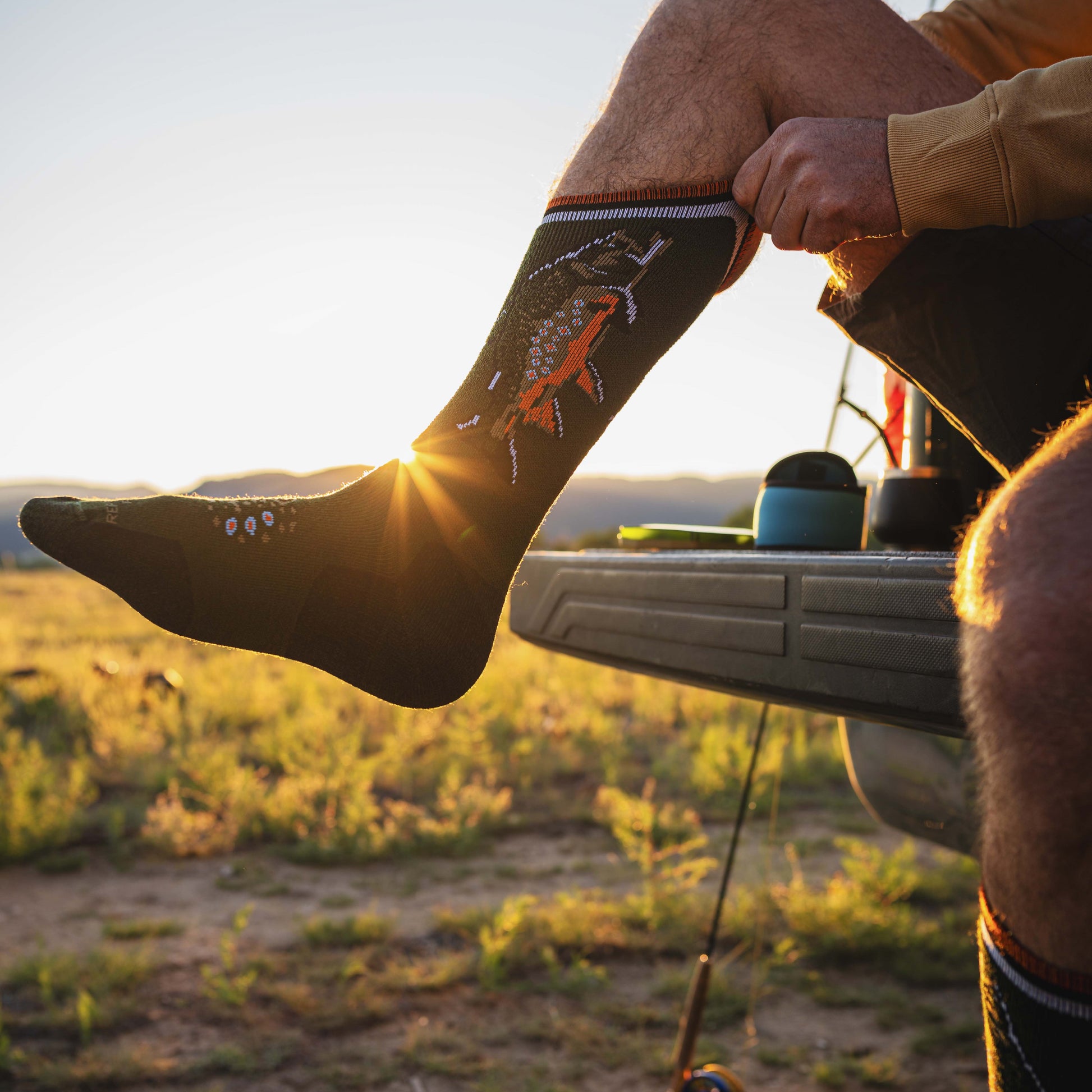 photo of person putting on a pair of brook trout socks in morning light
