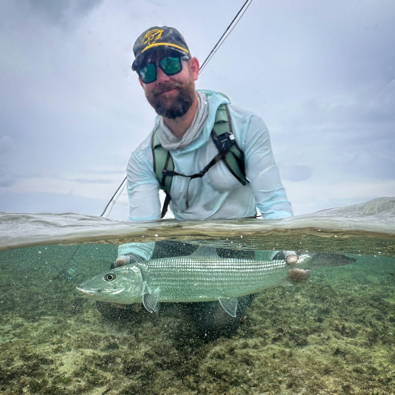 man holding bonefish in water with clearwater flolite on