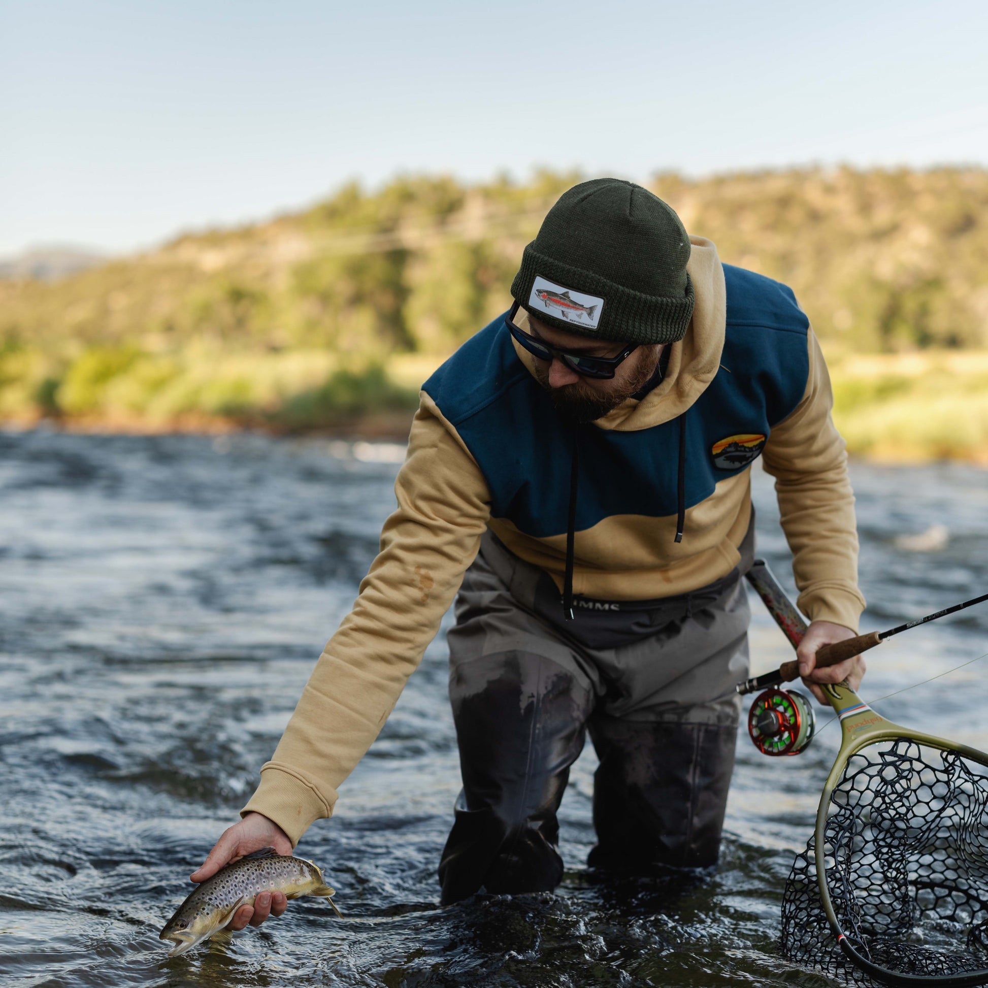 man standing in river holding a trout