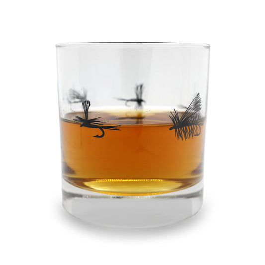 a clear old fashioned with dry flies around the center in black ink. the glass has a pour of brown water