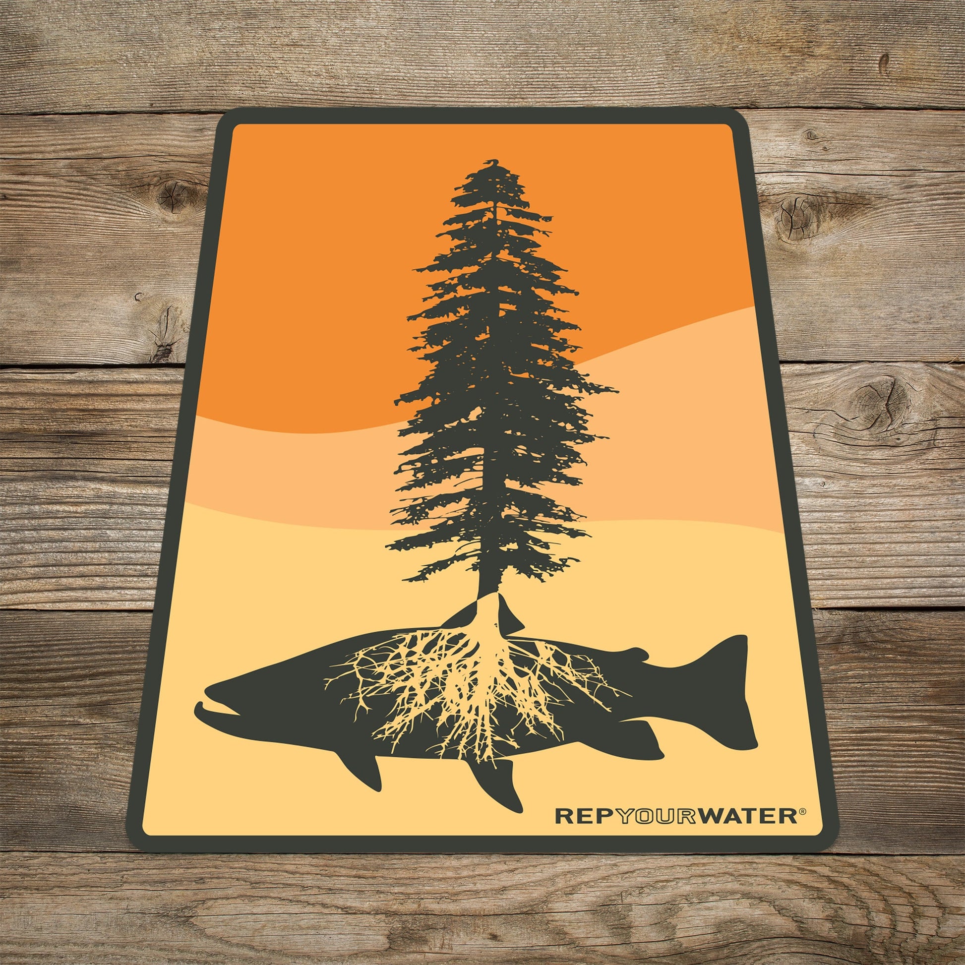 Sticker that shows shade of orange in the background and a tree and trout solhouette in black