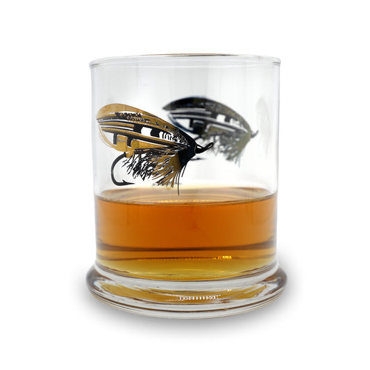 a clear glass with a pen and ink drawing of a classic salmon fly in black and gold