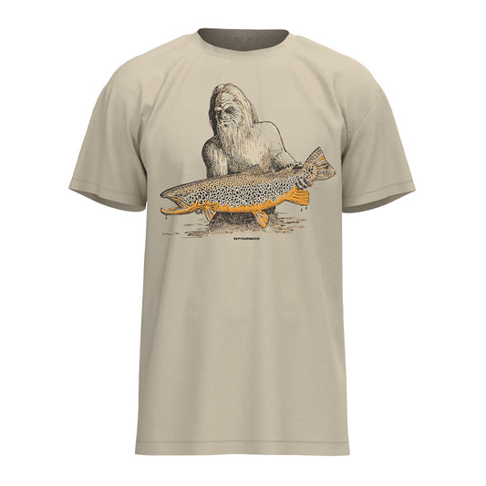 Tan tee shirt with a drawing of sasquatch holding a brown trout on the front