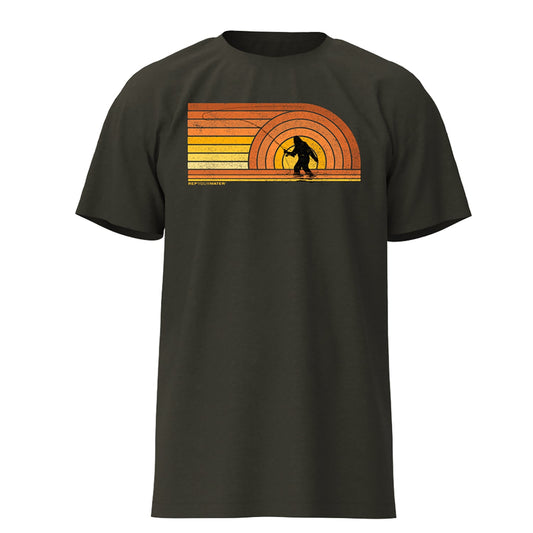 military heather green shirt with a picture of sasquatch casting a fly rod on the back and shades of orange and yellow making a retro sunset