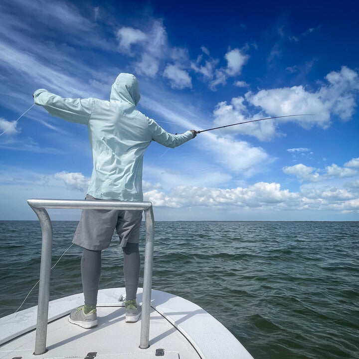 person casting a fly rod on a boat in a clearwater flolite sun hoody